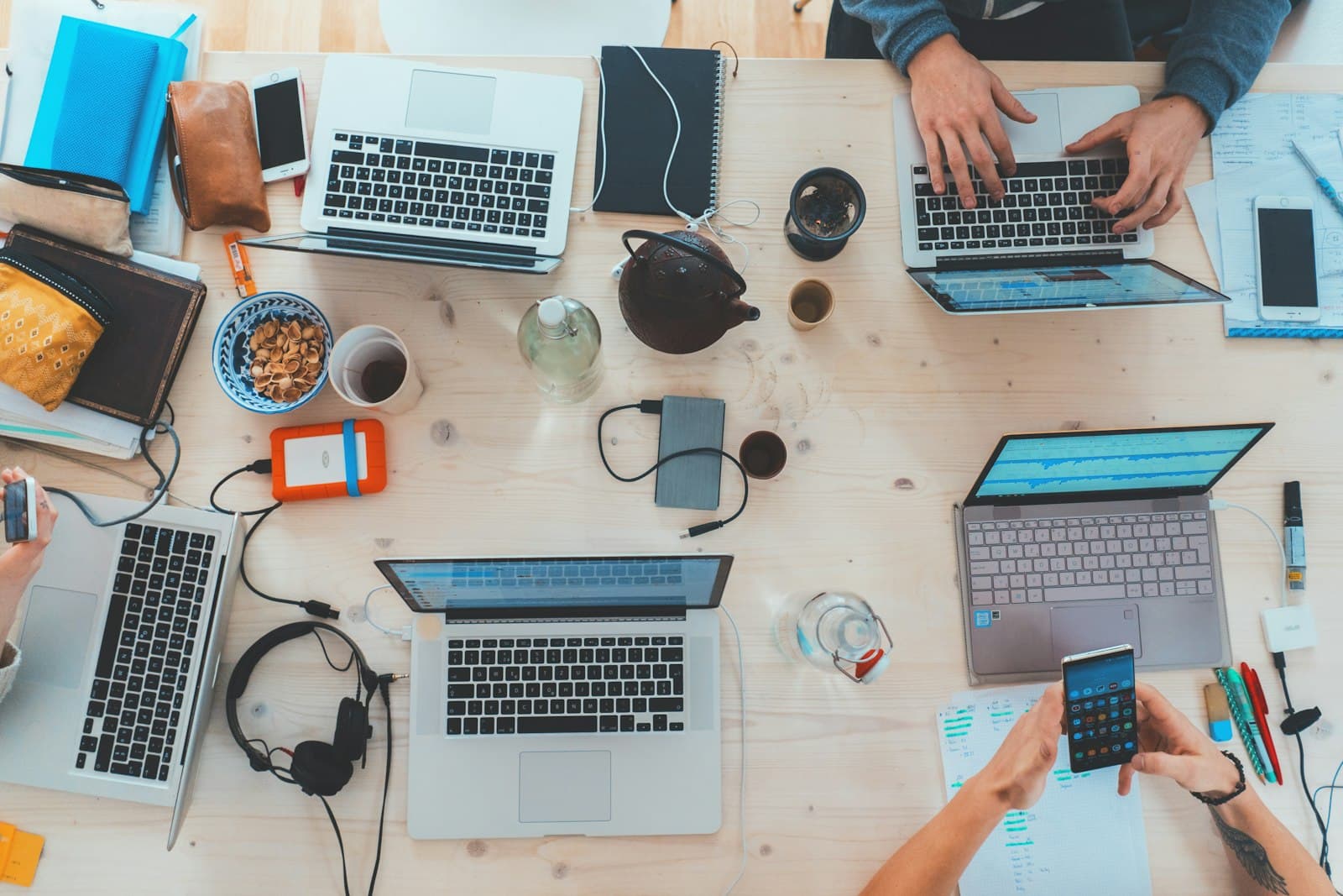 Overhead view of a team working at a shared desk with laptops