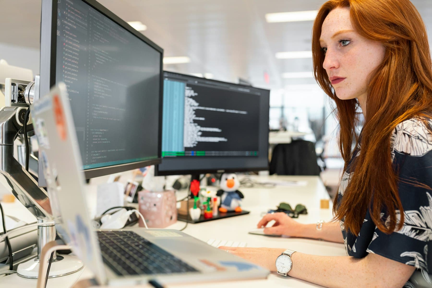 A developer reviewing code across two monitors