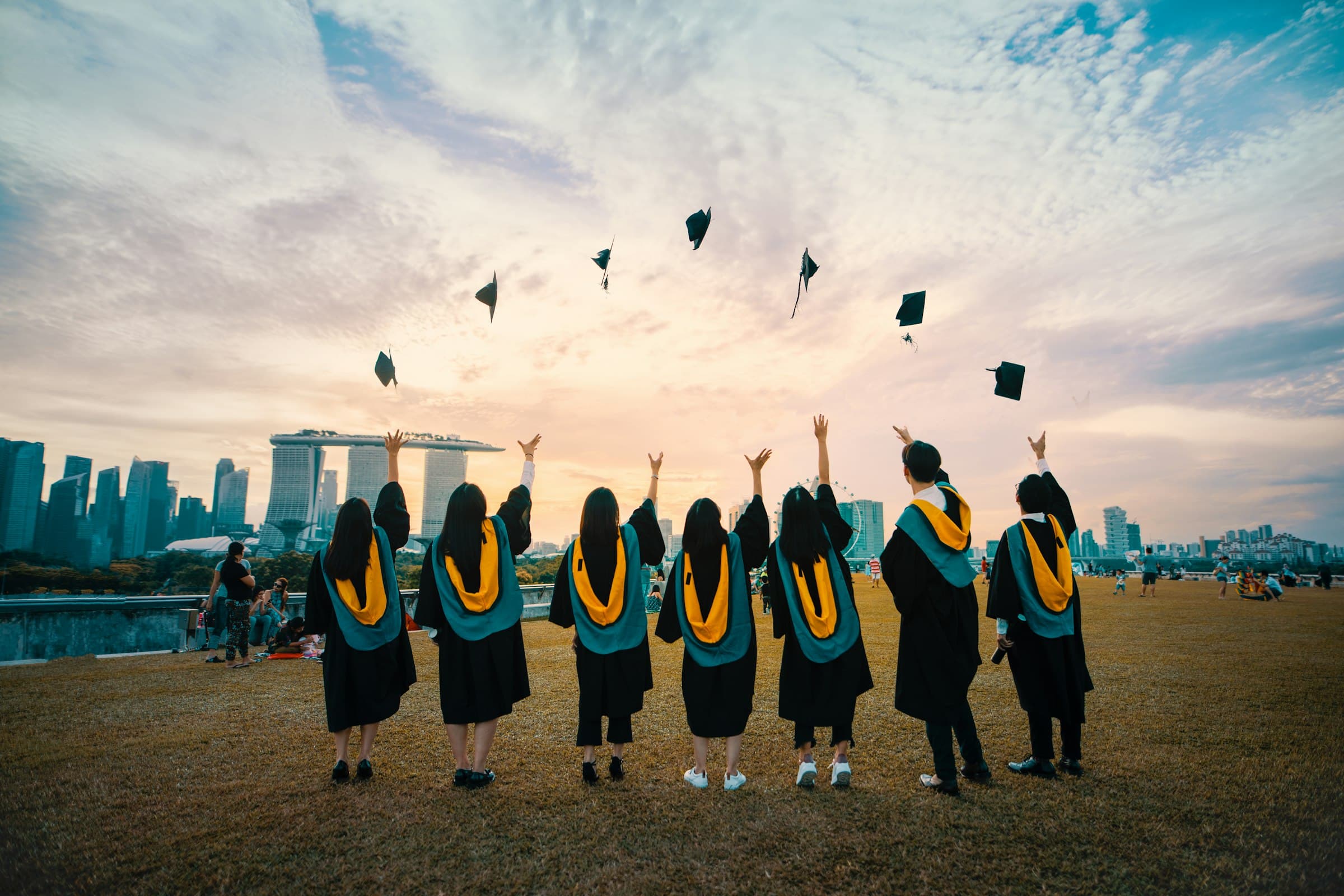 Graduates celebrating against a city skyline at sunset