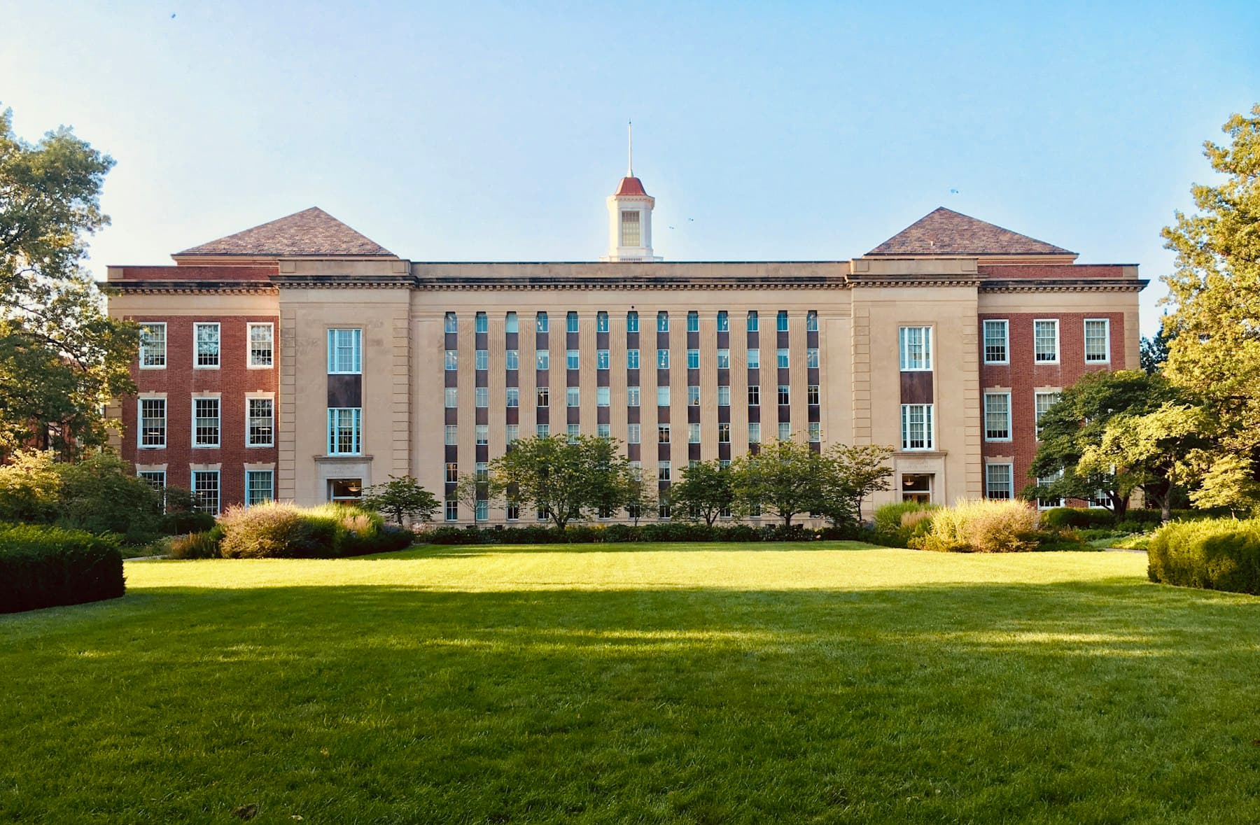 A historic university building surrounded by lawns and trees