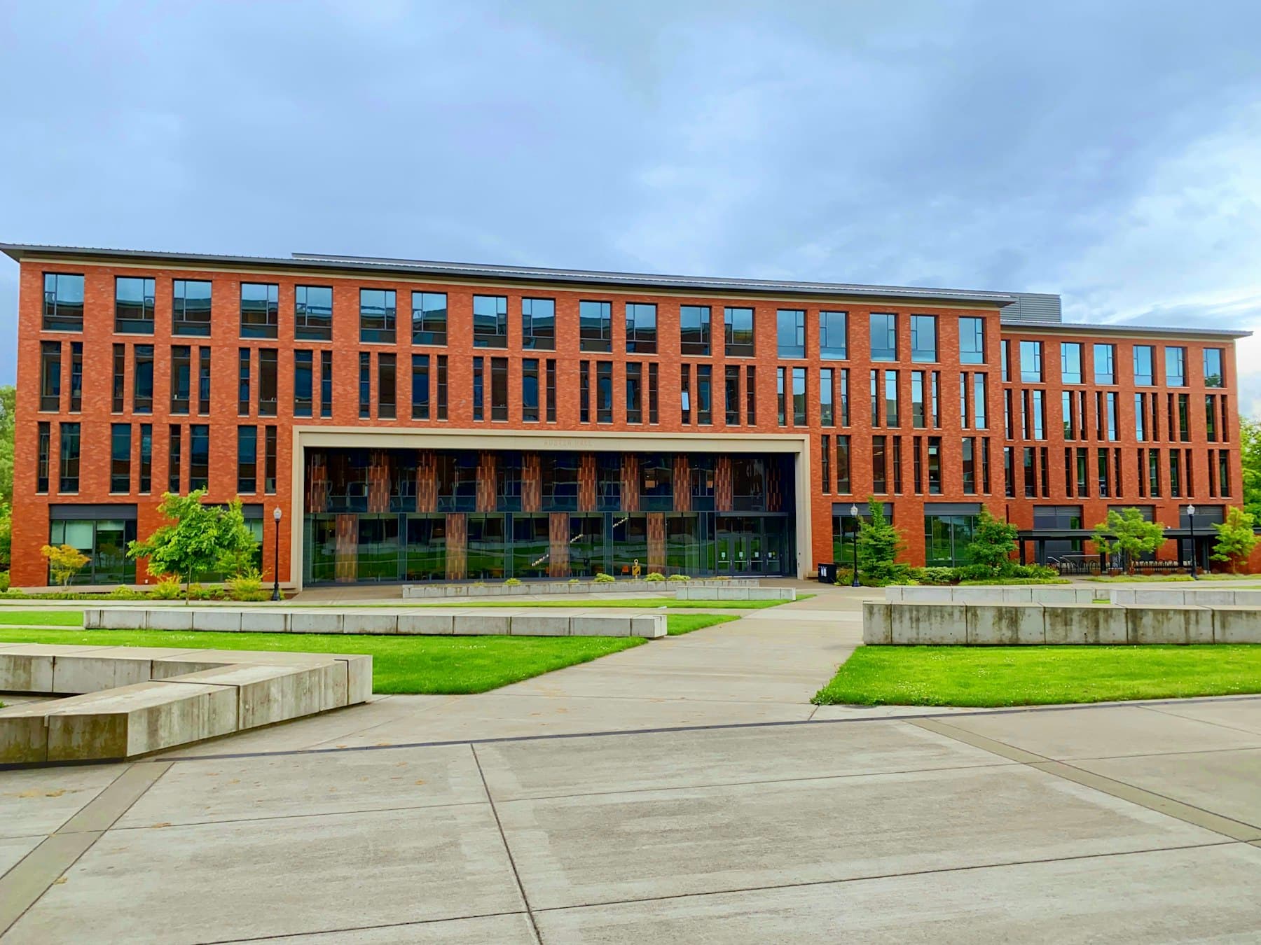 A modern red-brick university building with landscaped grounds
